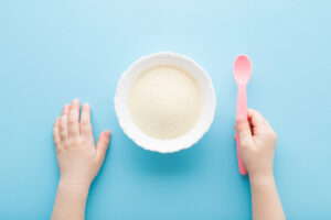 powdered medical food with a scoop held by a child’s hand