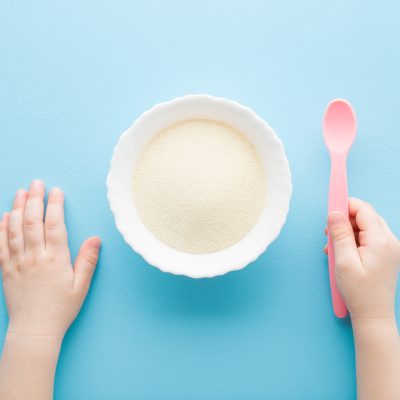 powdered medical food with a scoop held by a child’s hand